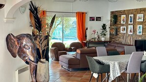 Un salon spacieux avec un grand canapé, une table à manger et des chaises, ainsi qu’une sculpture d’éléphant décorative.