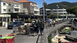 Un café avec des tables en terrasse, une rue piétonne et une montagne en arrière-plan.