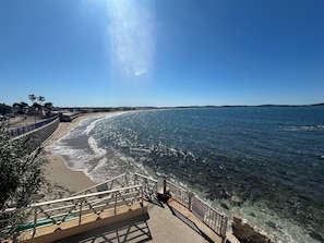 Un paseo marítimo con vistas despejadas al mar, una playa de arena y un litoral rocoso.