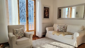 Una sala de estar con un sofá blanco, un sillón blanco y un espejo grande.