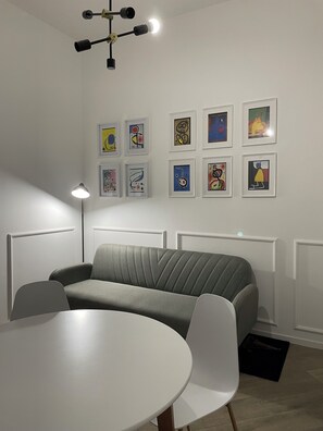 A modern room with a grey sofa, a round table, and a ceiling light fixture.