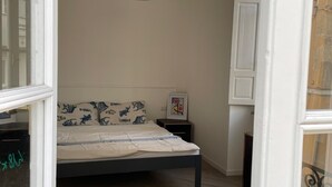 A bedroom with a bed, a hanging light fixture, a nightstand, and a wardrobe. - Alice's House a stone's throw from the sea and the old town of Neptune (Nettuno)