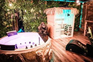 A spa area with a hot tub, a wooden cabinet, and a gorilla statue. - Eden Tropical Love Room (Breuches)