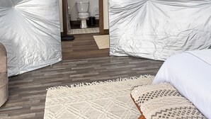 Quarto com design geométrico único no teto, piso de madeira e cama com roupa de cama estampada.