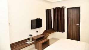 Een hotelkamer met een bed, een aan de muur bevestigde televisie, een bureau met stoel en een houten garderobe.
