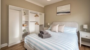 A bedroom with a bed, a wardrobe, a nightstand, and a wall-mounted lamp. - Stunning home over looking Belfast City, 11 minutes to City Centre (Castlereagh)
