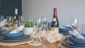 A dining table set with blue bowls, wine glasses, and bottles, surrounded by decorative elements like a potted plant and white flowers. - Stunning home over looking Belfast City, 11 minutes to City Centre (Castlereagh)