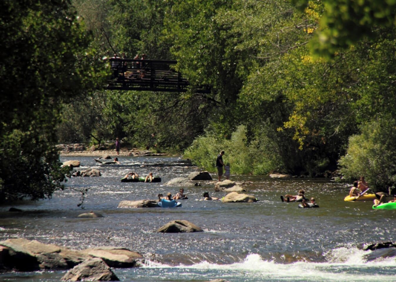 Ein Fluss mit Rafting-Enthusiasten und Personen auf Felsen.