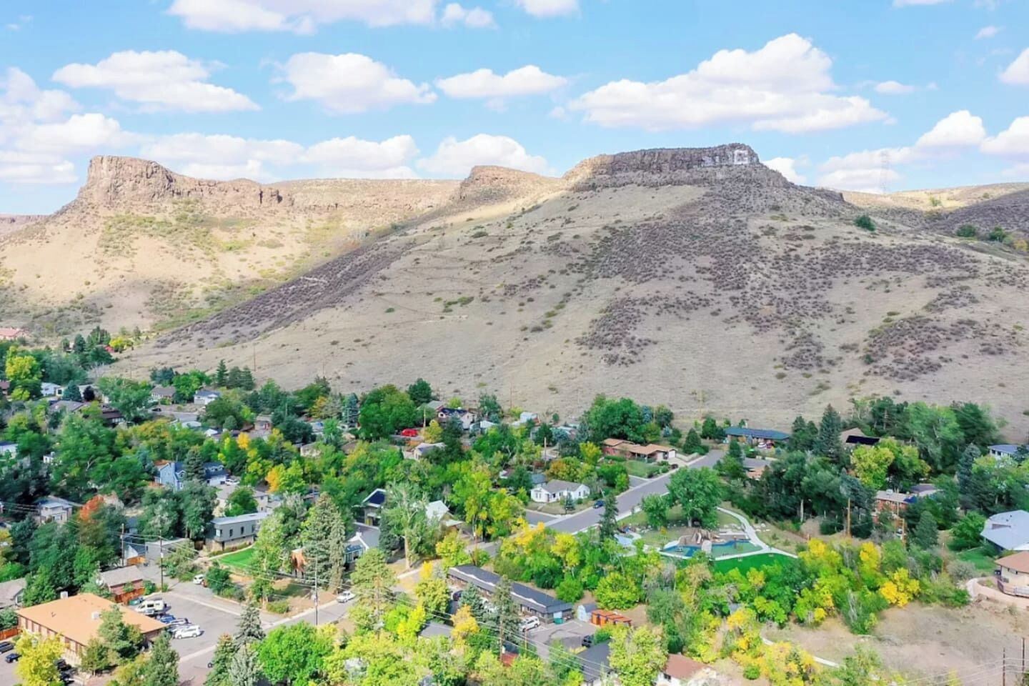 A residential area with houses, trees, and a hill with a flat top.