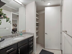 A bathroom with a granite countertop sink, a mirror, a towel rack, and a door leading to a closet. - Red Rocks Retreat | Minutes to Shows, Hikes, Shops (Golden)