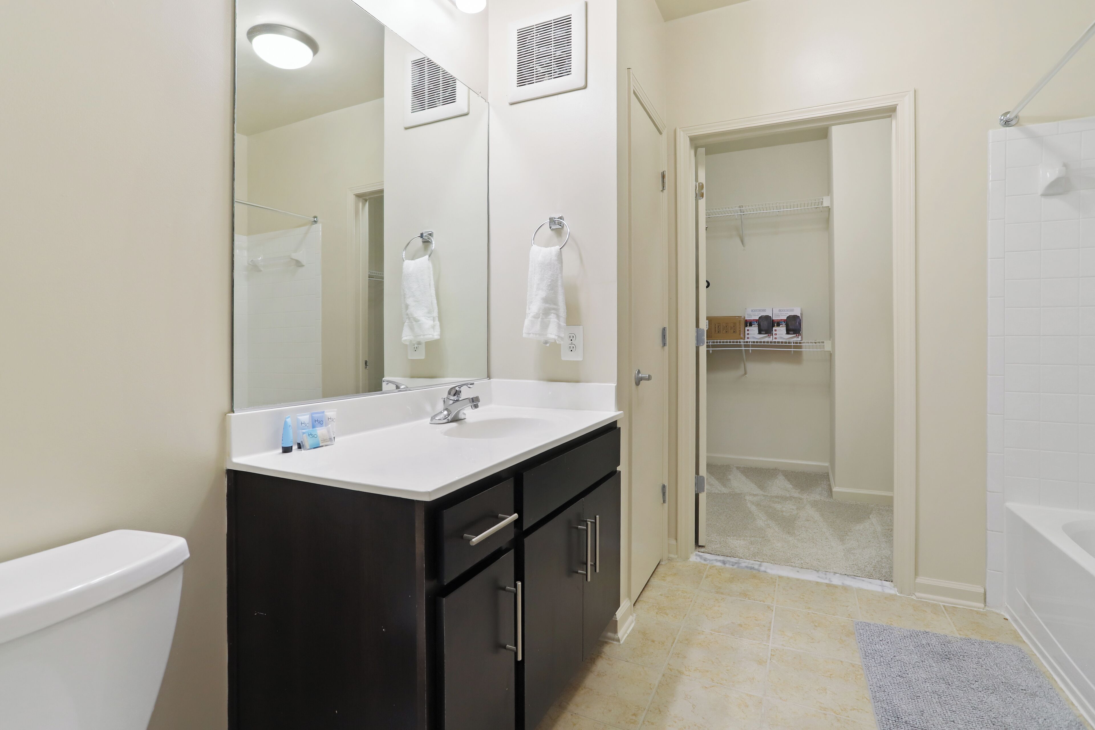 A bathroom with a double sink, a mirror, a toilet, and a shower area.