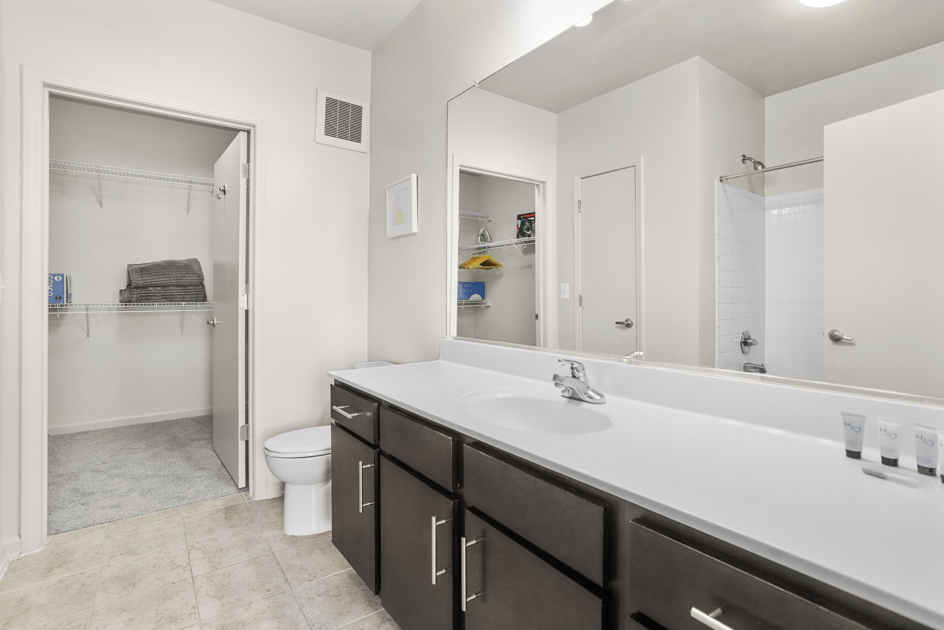 A modern bathroom with a white vanity, a large mirror, and a walk-in shower.