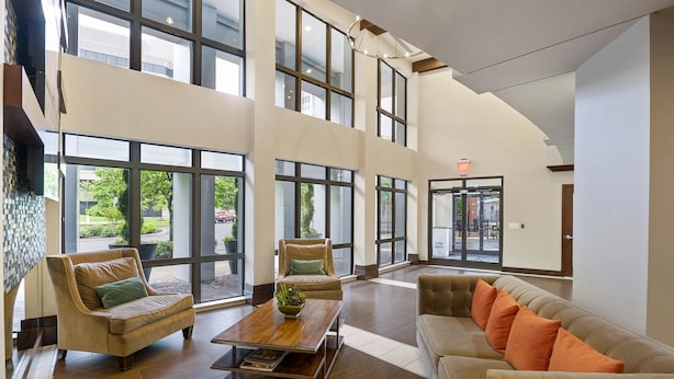 A spacious lobby with high ceilings, large windows, and modern furniture. - DC Charm in Crystal Apartments (Arlington)