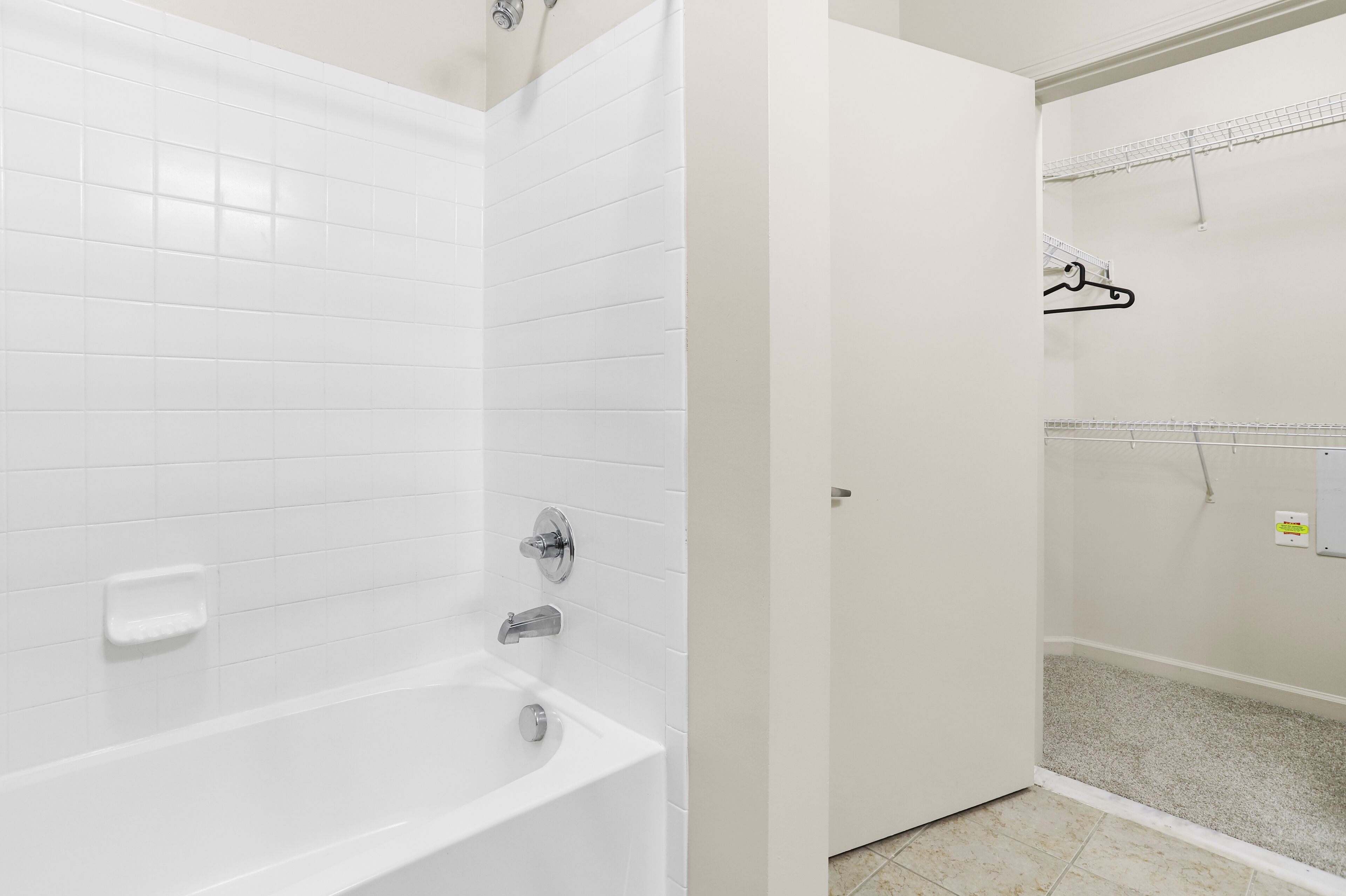 A bathroom with a white bathtub, a shower, and a tiled floor.