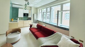 Een moderne keuken met een eethoek, een rode bank en uitzicht op de straat.