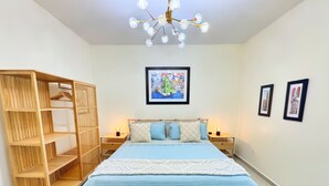 Een slaapkamer met een groot bed, een houten garderobe en twee nachtkastjes met lampen.
