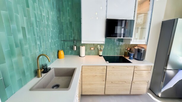 Een moderne keuken met een spoelbak, aanrecht en houten kastjes.