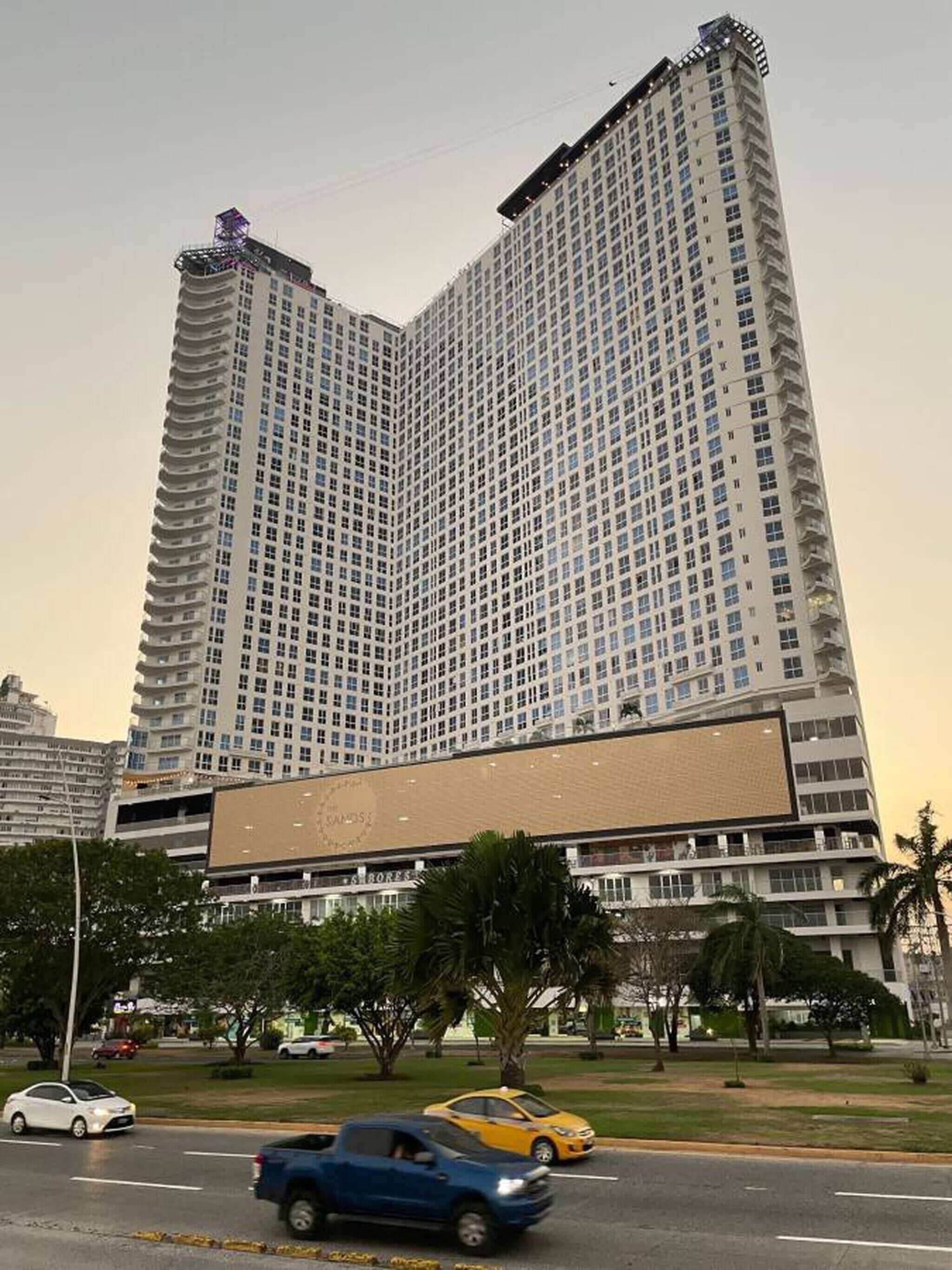 Un grand immeuble moderne, avec une façade composée d’une grille de fenêtres et de balcons.