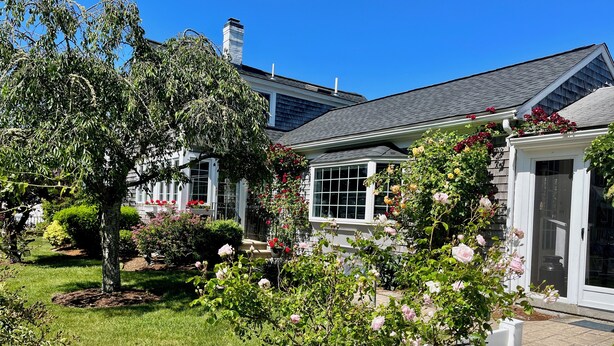 A house with a well-maintained garden, a white picket fence, and a garage door.
