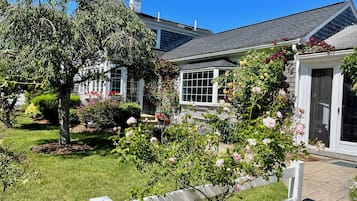 Una casa amb un jardí ben cuidat, una tanca blanca de palets i una porta de garatge.