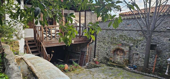 A stone building with a wooden staircase leading to a balcony. - Birgi Mai Siyah Konak (Birgi)