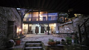 Une cour dallée en pierre avec un escalier menant à une terrasse en bois et un balcon.