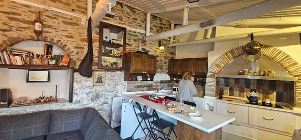 Una cocina acogedora con pared de piedra, armarios de madera y una isla central con taburetes de bar.
