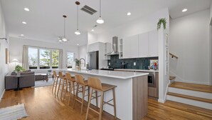 A modern kitchen with a central island, bar stools, and a dining area with a sofa and coffee table. - Amazing Panoramic Views From This Luxury Retreat, Enjoy The Sauna On Top Deck. (Chattanooga)