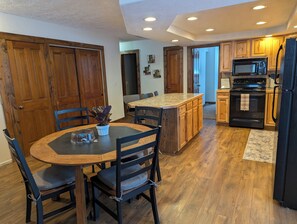 A modern kitchen with wooden cabinets, a central island, and a dining area with chairs.