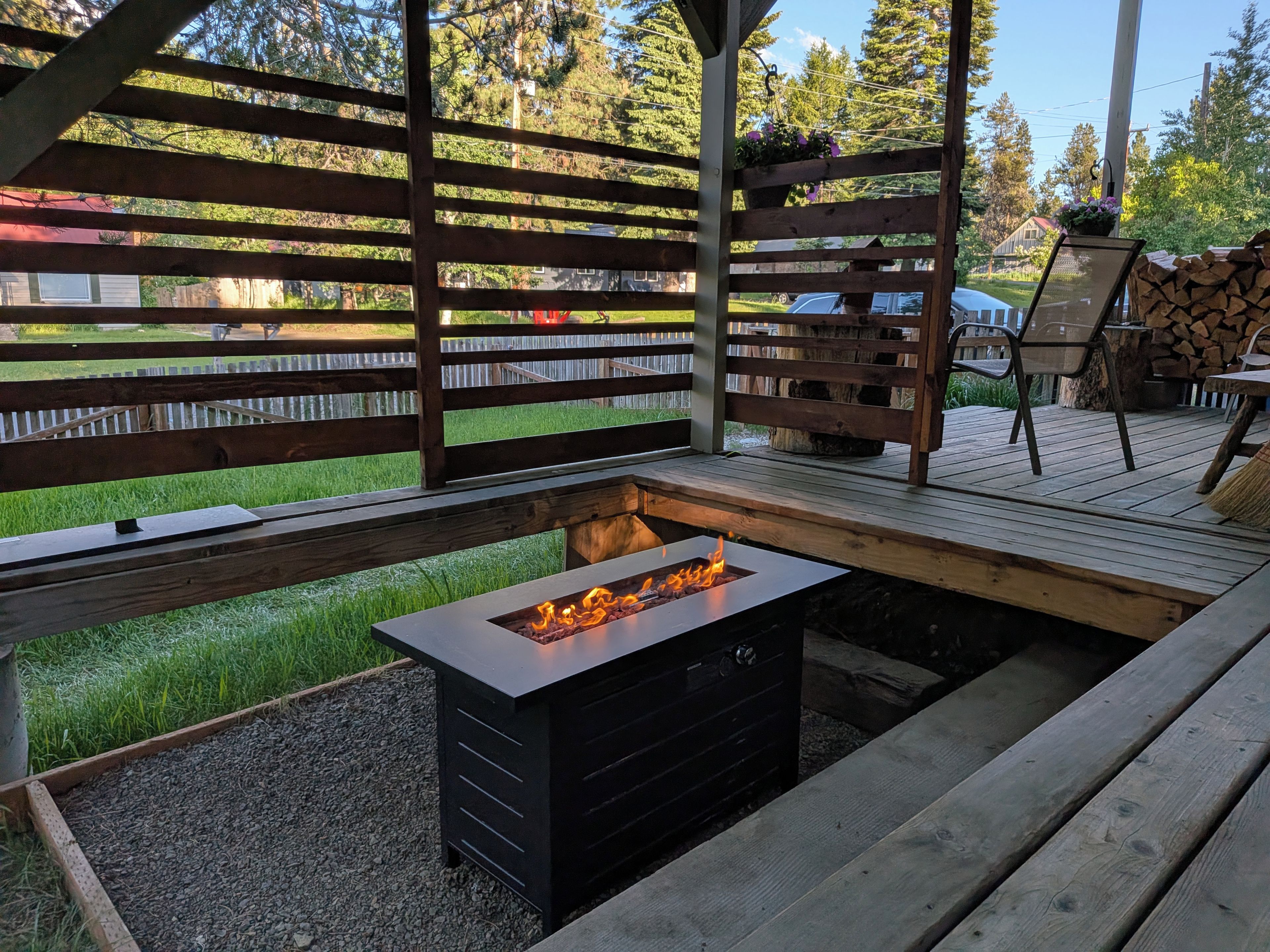 A wooden deck with a built-in fire pit and outdoor furniture.