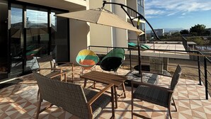 A rooftop terrace with outdoor furniture, a large umbrella, and a view of a modern building. - Modern 2 bed/2 bath, 1st floor condo. 
Casa Ventosos (Calypso 102). (La Ventana)