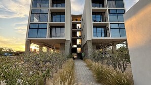 A modern building with a central atrium, surrounded by a landscaped pathway. - Modern 2 bed/2 bath, 1st floor condo. 
Casa Ventosos (Calypso 102). (La Ventana)