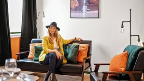A modern living room with a sofa, colorful cushions, a framed artwork on the wall, and a table with a glass. - The Jewel Box 3BR Apt, JQ Birmingham with Parking (birmingham)