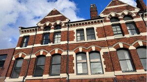 A multi-story brick building with arched windows and a prominent gabled roof. - The Jewel Box 3BR Apt, JQ Birmingham with Parking (birmingham)