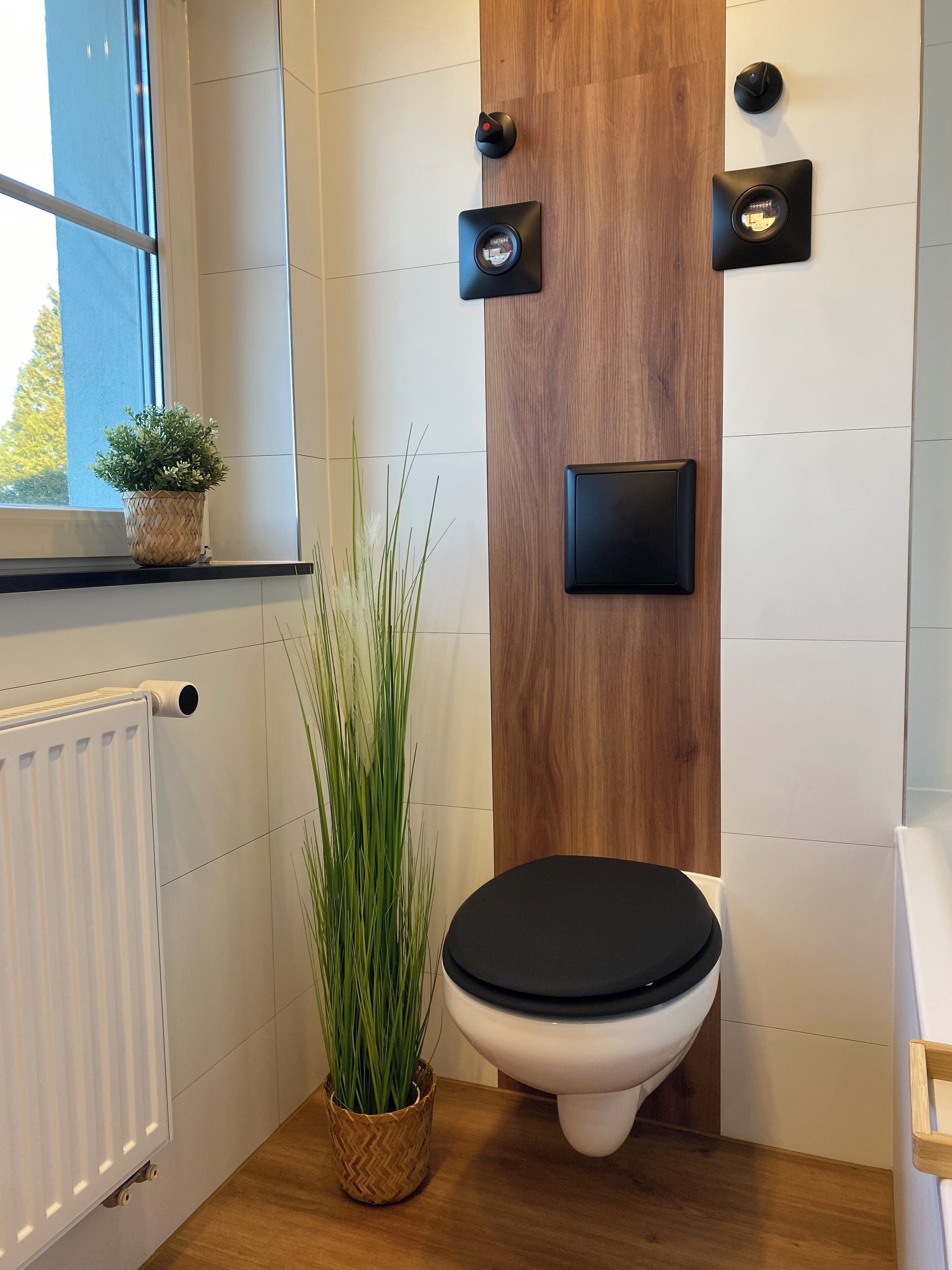 Un baño moderno con una pared de acento de madera, un inodoro, un radiador y una planta en maceta.