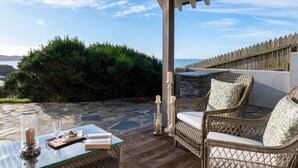 A covered outdoor seating area with wicker furniture, a glass table, and candles. - Yellow Sands -  a house that sleeps 10 guests  in 5 bedrooms (Thurlestone)