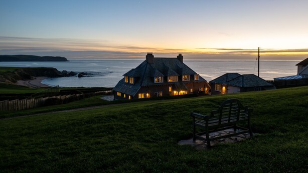 A coastal house with a thatched roof, a grassy lawn, and a bench. - Yellow Sands -  a house that sleeps 10 guests  in 5 bedrooms (Thurlestone)