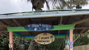 En tiki-bar med en skylt som visar att middagen är serverad och en klocka som visar att det är klockan fem någonstans.
