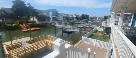A marina with boats docked, wooden walkways, and a view of residential buildings in the background.