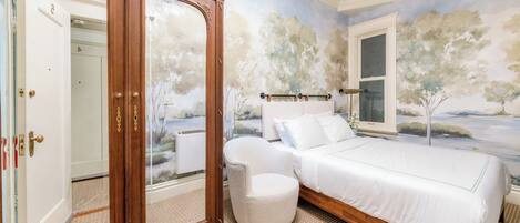 A bedroom with a bed, a large mirror, and a window.
