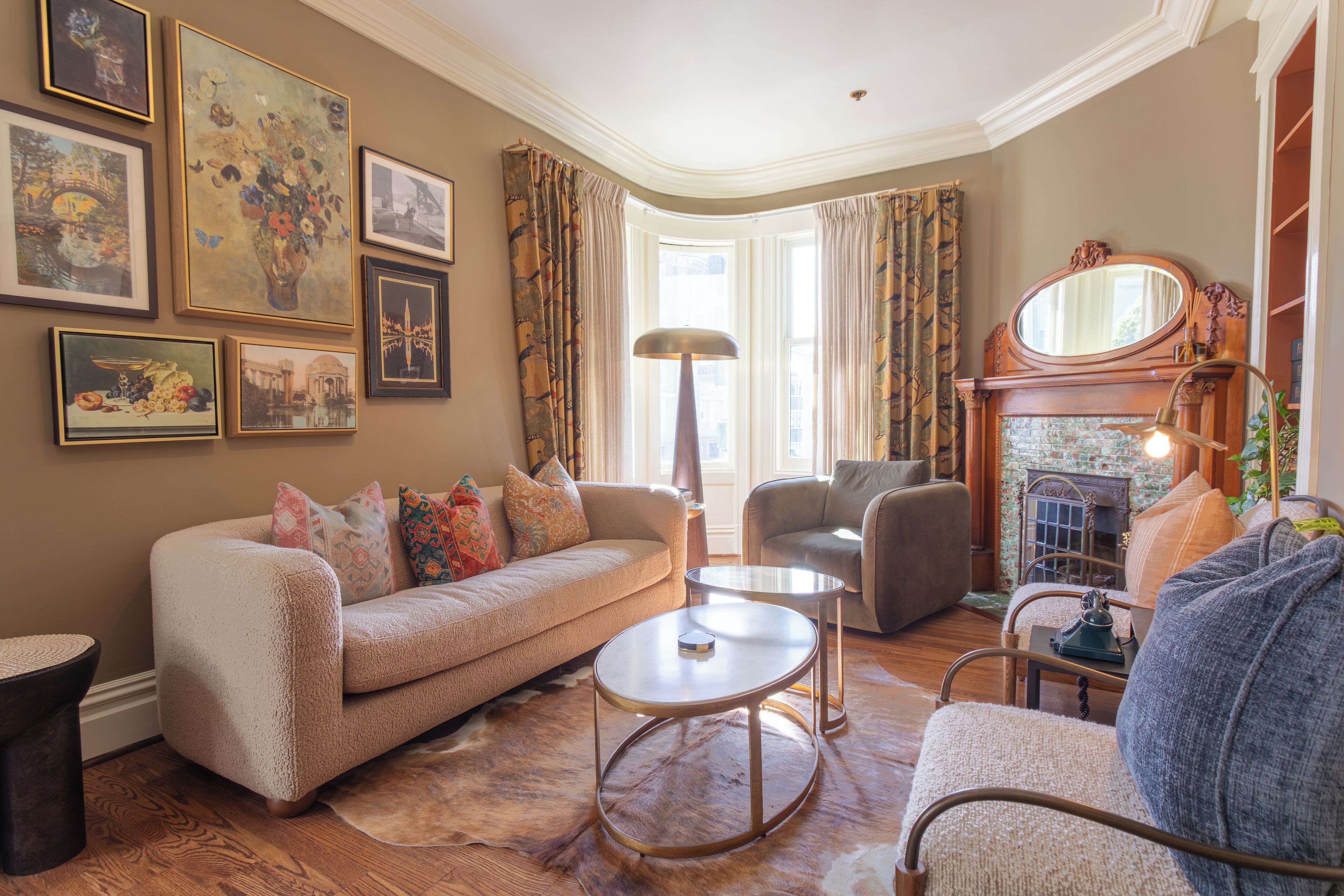 A cozy living room with a sofa, armchair, and coffee table, a fireplace, and framed artwork on the walls.