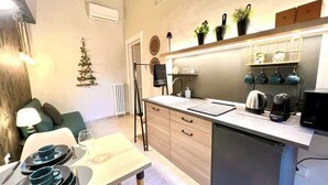 A modern kitchen with a dining area, featuring a wooden table set for two, a small Christmas tree, and a built-in oven.
