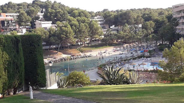 En resort med swimmingpool, strand og frodig beplantning.