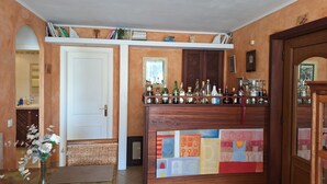En bar med en trædisk, reoler med bøger og et udvalg af flasker.