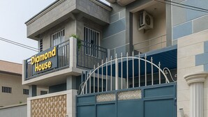 Un immeuble de deux étages doté d’une entrée fermée par un portail et d’un balcon.