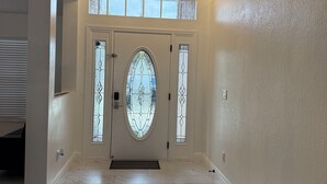 A spacious hallway with a large, ornate door featuring stained glass panels and a circular window. - The Perfect Gateway Home with a large pool area, Gazebo, all fenced in. (Spring Hill)