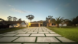 A residential driveway leading to a house with a garage, a lawn, and a palm tree. - The Perfect Gateway Home with a large pool area, Gazebo, all fenced in. (Spring Hill)