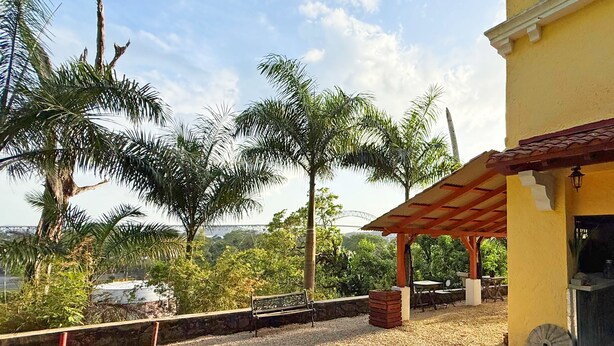 A covered outdoor area with a bench, tables, and a small building with a tiled roof. - Panama View House (Panamá)