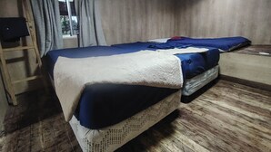 A room with two beds, a wooden floor, a window with curtains, and an air conditioning unit. - Panama View House (Panamá)