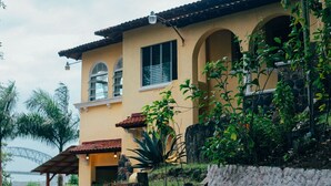 A two-story building with a yellow facade, arched windows, and a covered patio area. - Panama View House (Panamá)